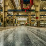 Wide view of an empty industrial warehouse with visible cranes and metal structures.